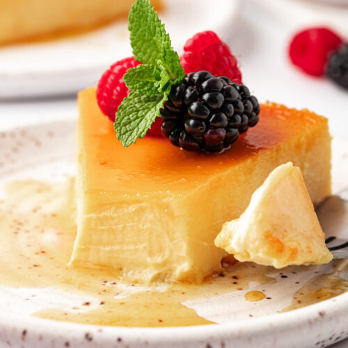 Slice of flan with mint, raspberries, and blackberries on top.