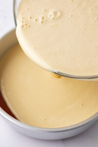 Pouring flan mixture into cake pan.