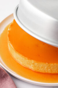 Removing the flan from the cake pan onto platter.