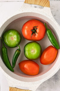 Tomatoes, tomatillos, and peppers in boiling water to make homemade salsa.