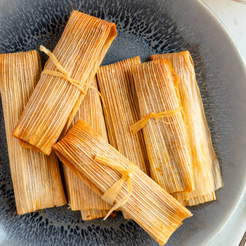 Plate with Mexican tamales wrapped in corn husks.