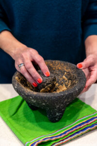 Grinding spices with a molcajete to make tamales from scratch.